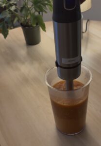 the tomatoes and cashews are being blended with a hand blender for the butter chicken gravy